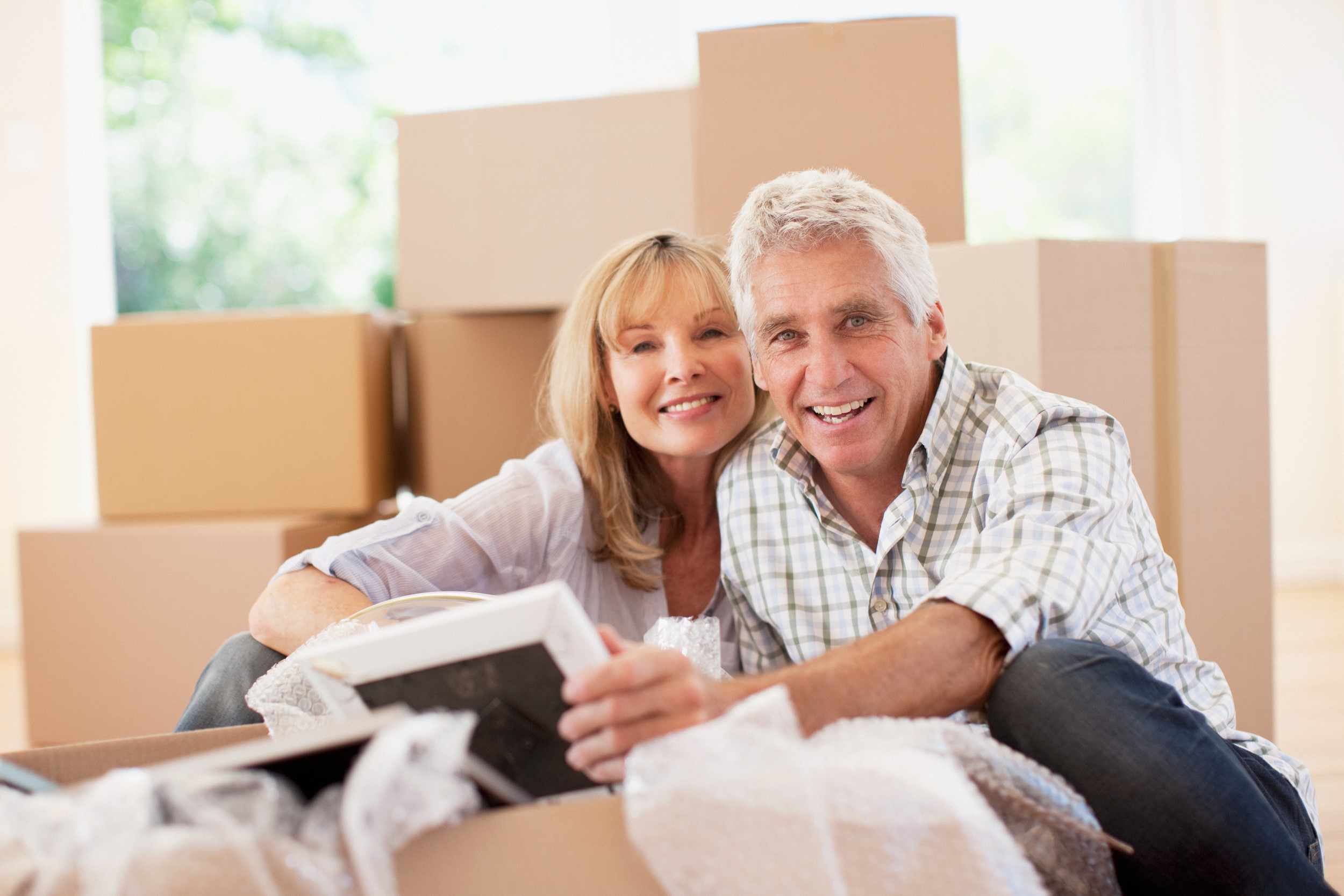 Older couple smiling in front of boxes