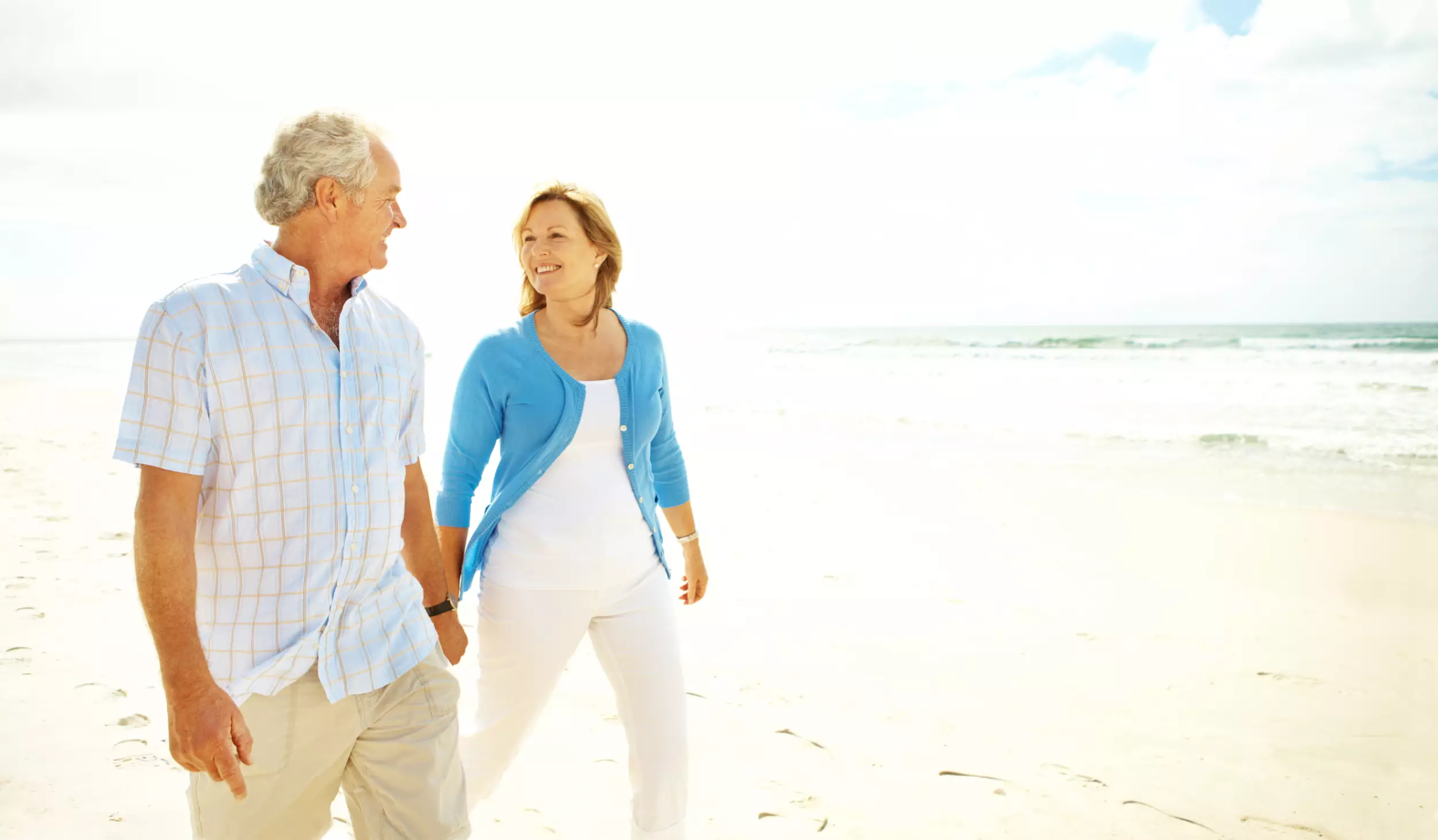 Happy older couple holding hands on the beach